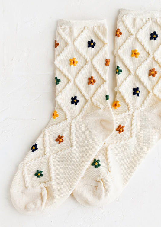 A pair of cream socks with diamond pattern and florals.