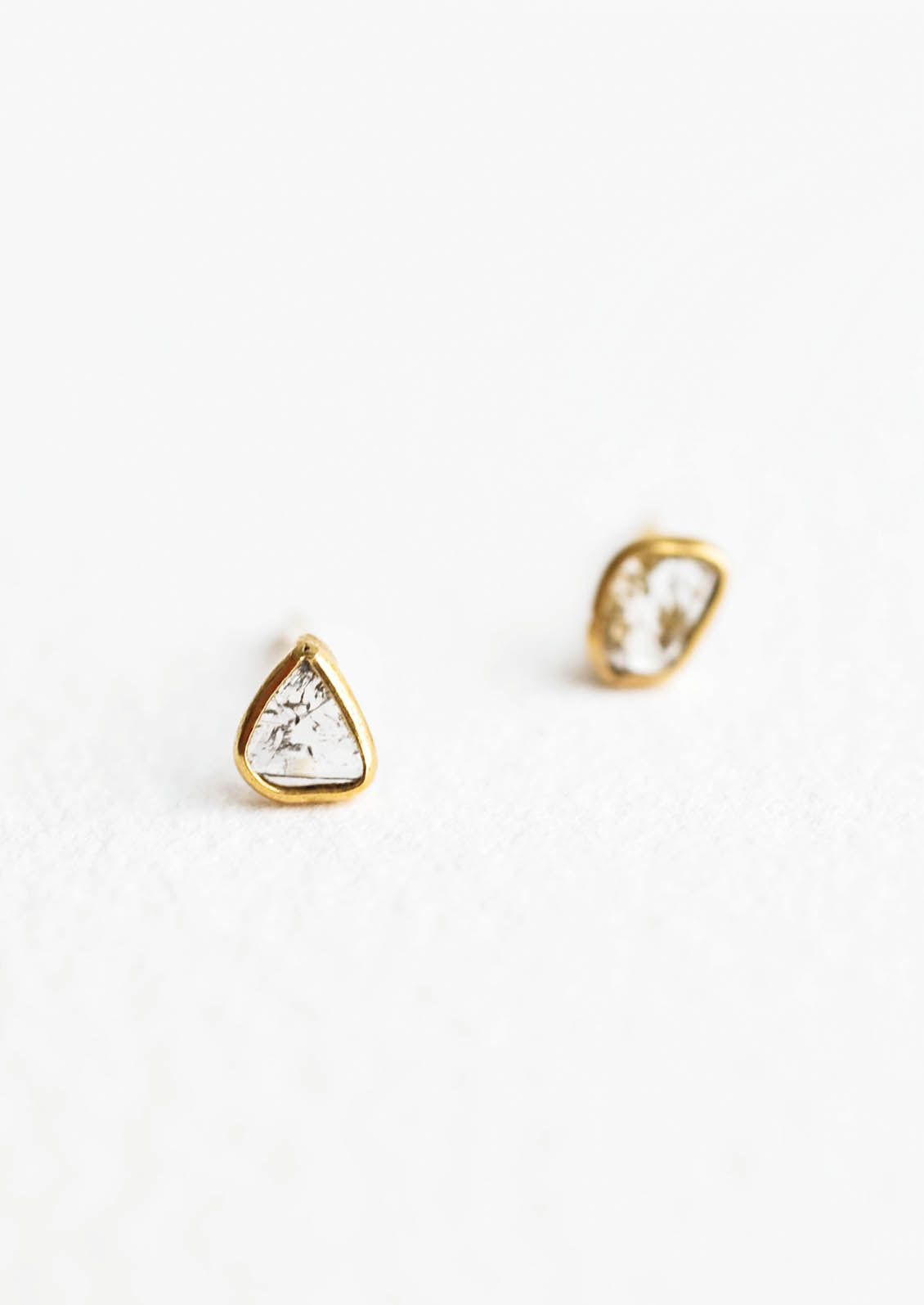 Organically shaped stud earrings with small diamond slice surrounded by brass metal trim