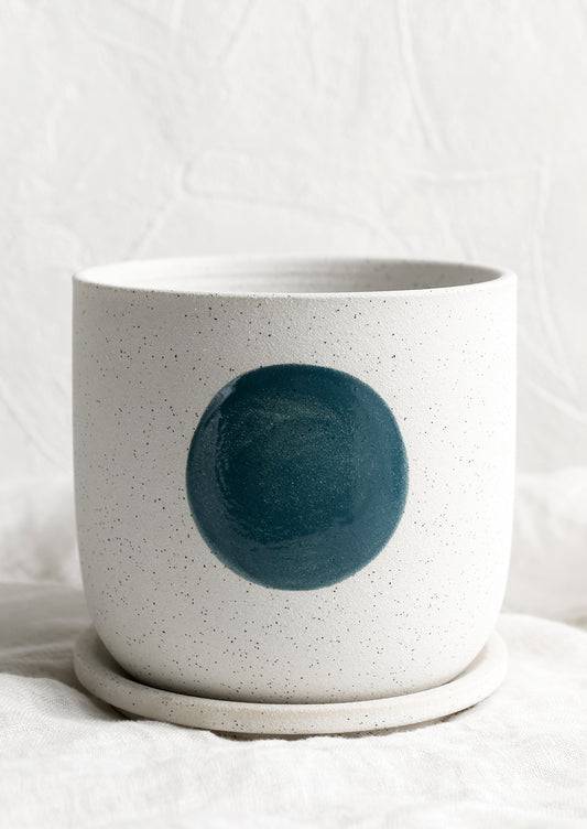 A white ceramic planter with blue dot.