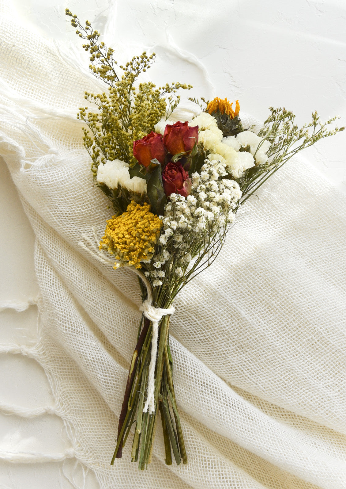 A bouquet of dried flowers in a red, yellow and white mix.