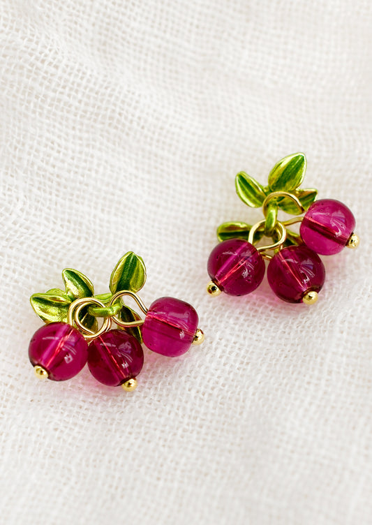 A pair of earrings made to resemble cranberries, made with round pink beads.