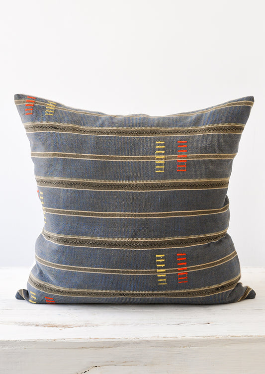 An indigo and dark grey striped pillow with yellow and red dash embroidery.