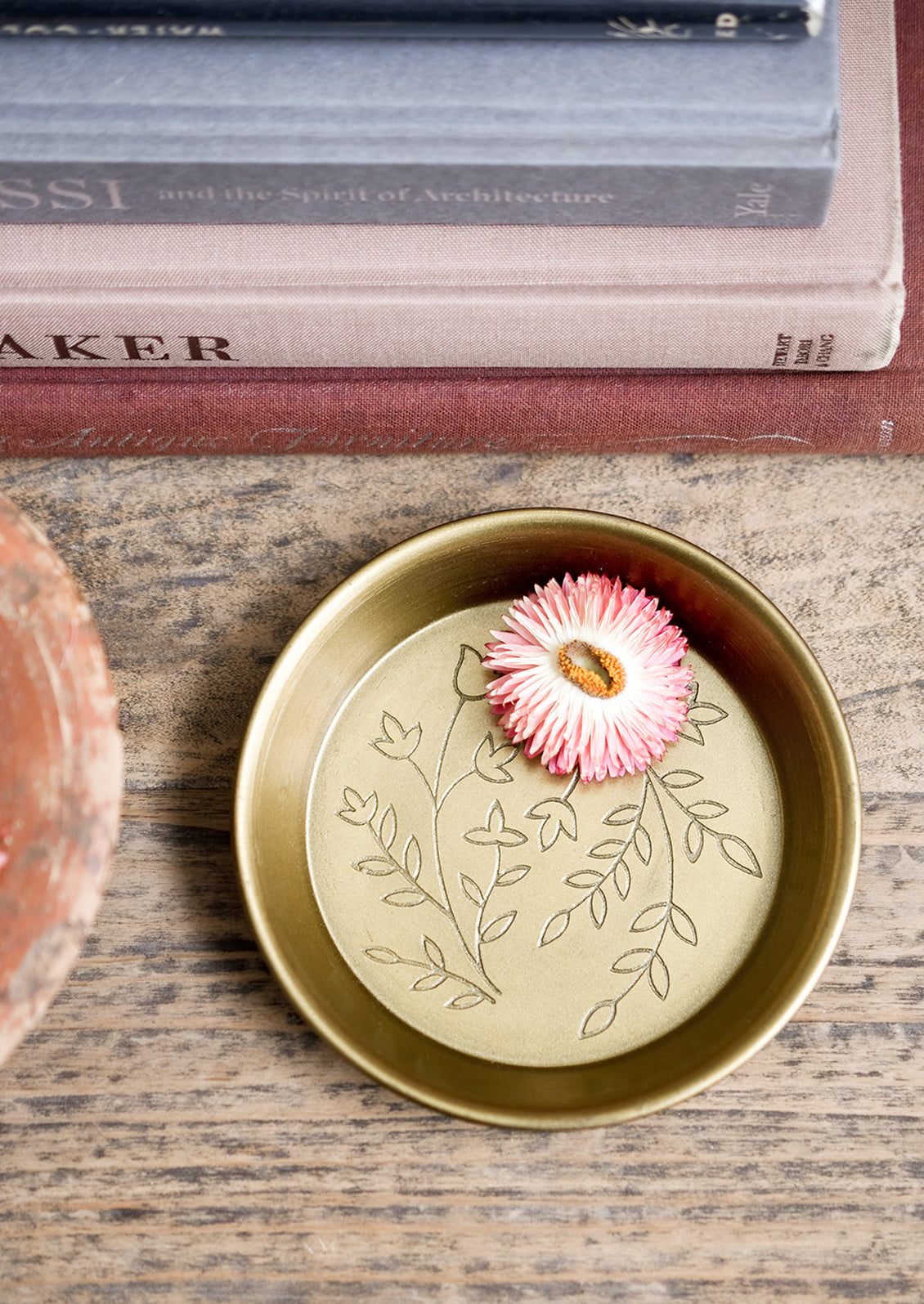 A small, round and shallow brass dish with floral engraving.