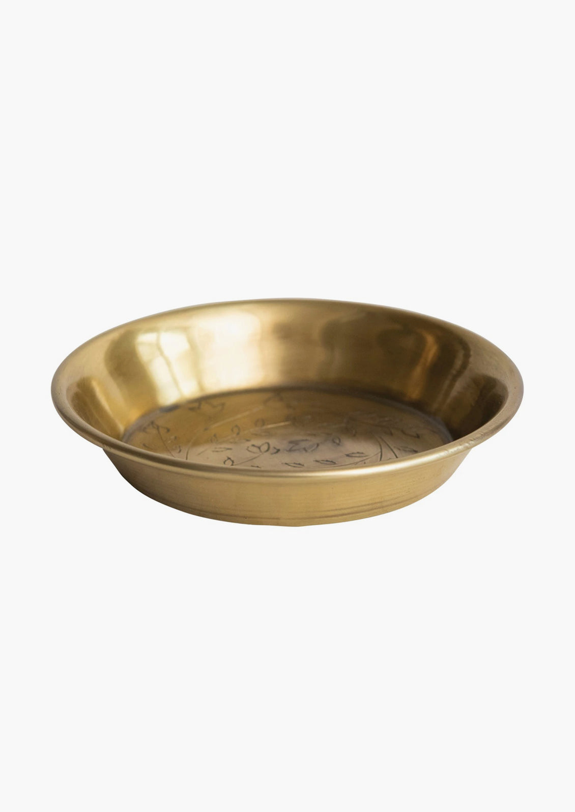 A small, round and shallow brass dish with floral engraving.