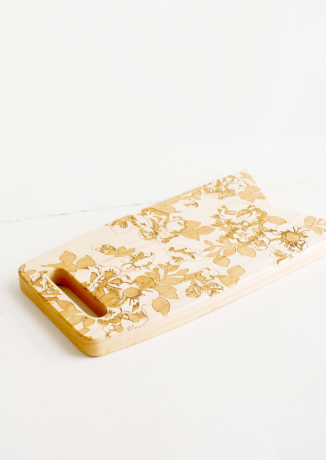 Flag shaped maplewood cutting board with handle cutout, lasercut floral pattern