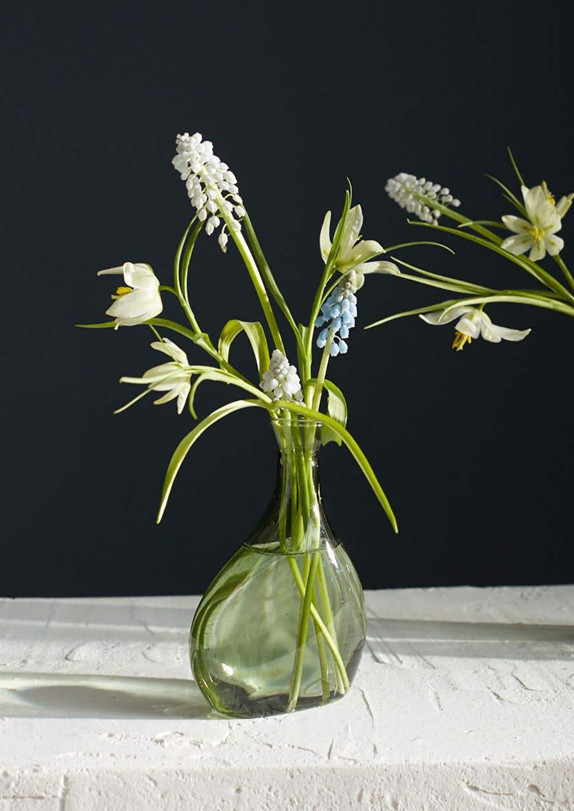 A tall, asymmetric glass vase in translucent green glass.