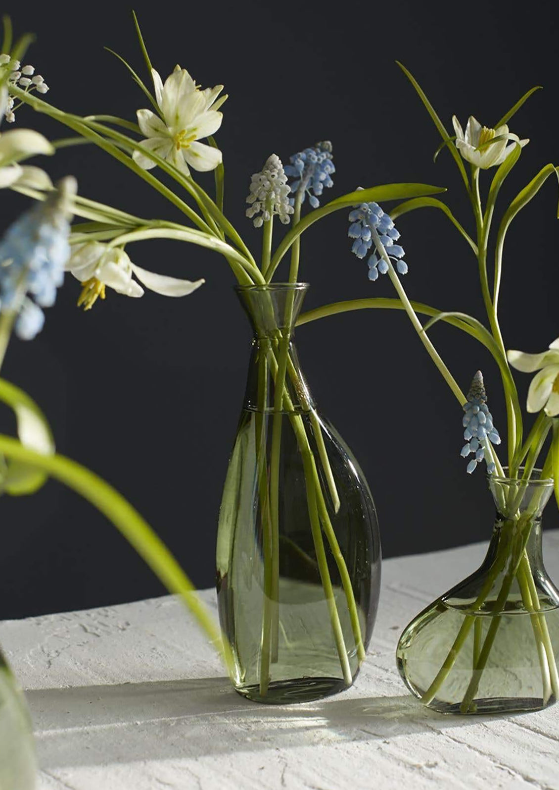 A short, asymmetric glass vase in translucent green glass.