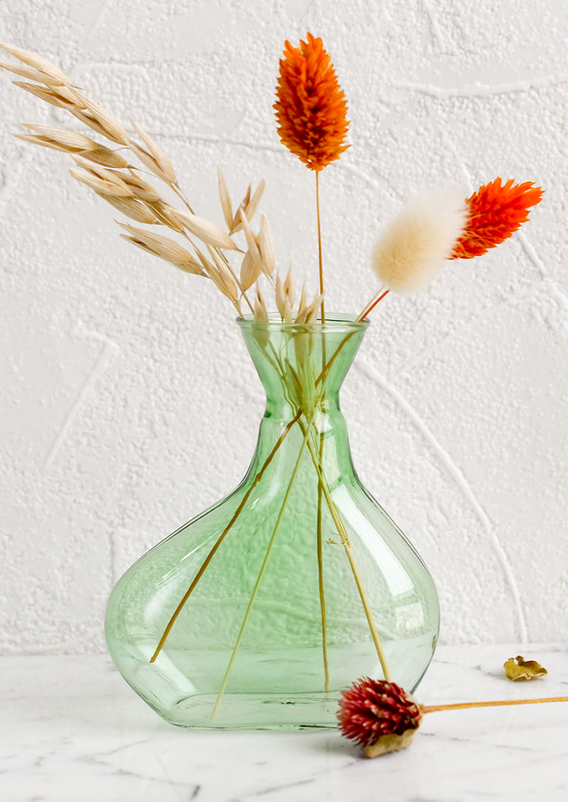 A short, asymmetric glass vase in translucent green glass.