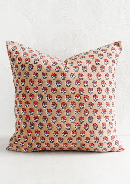 A block printed pillow in light brown with red and dusty blue flower print.