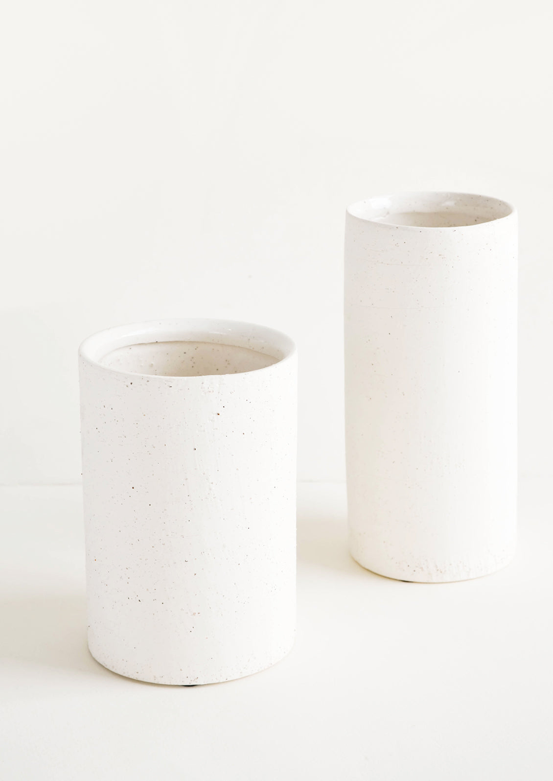 Vases made from white, textured concrete-like material in two different sizes, short and tall