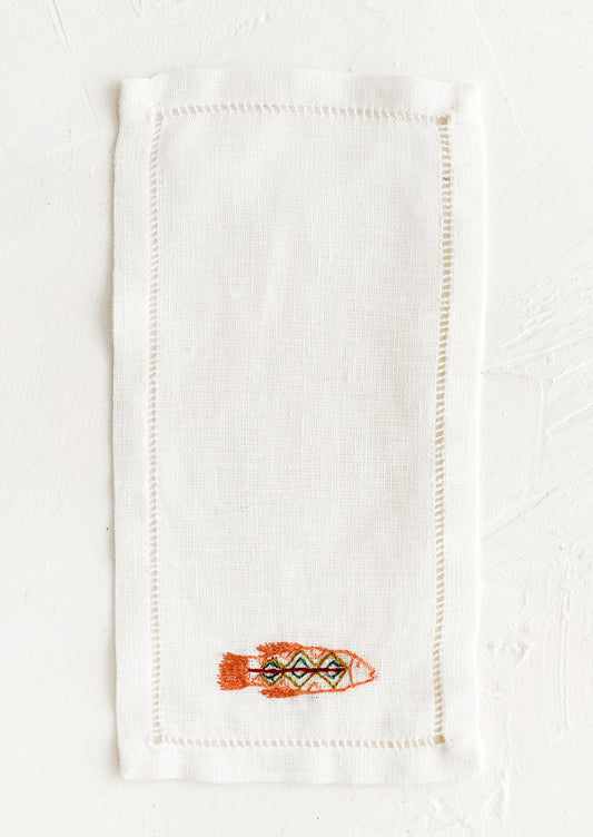 An white linen cocktail napkin with embroidered fish.