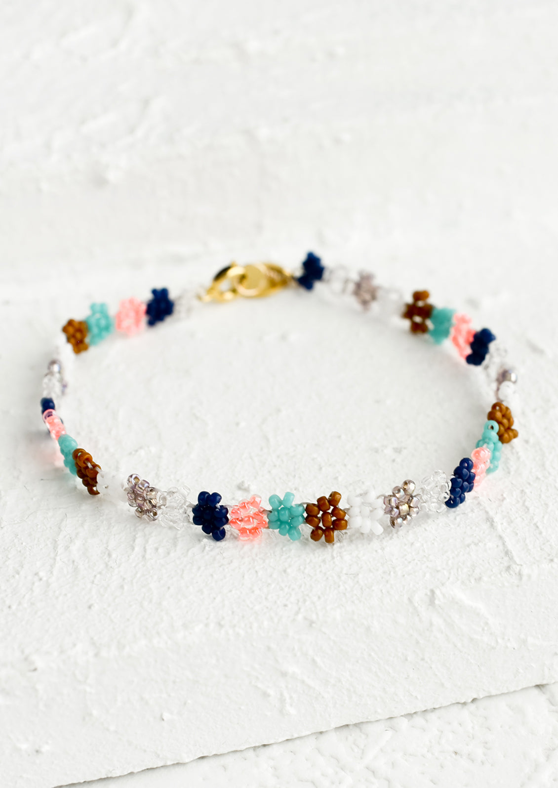 A beaded bracelet in flower shape in neon peach, turquoise, white and navy.