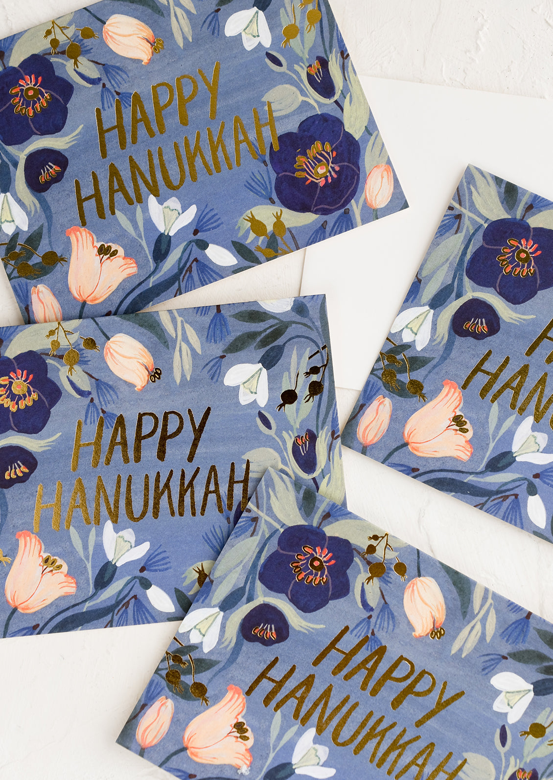 Greeting cards with blue floral print reading "happy hanukkah".