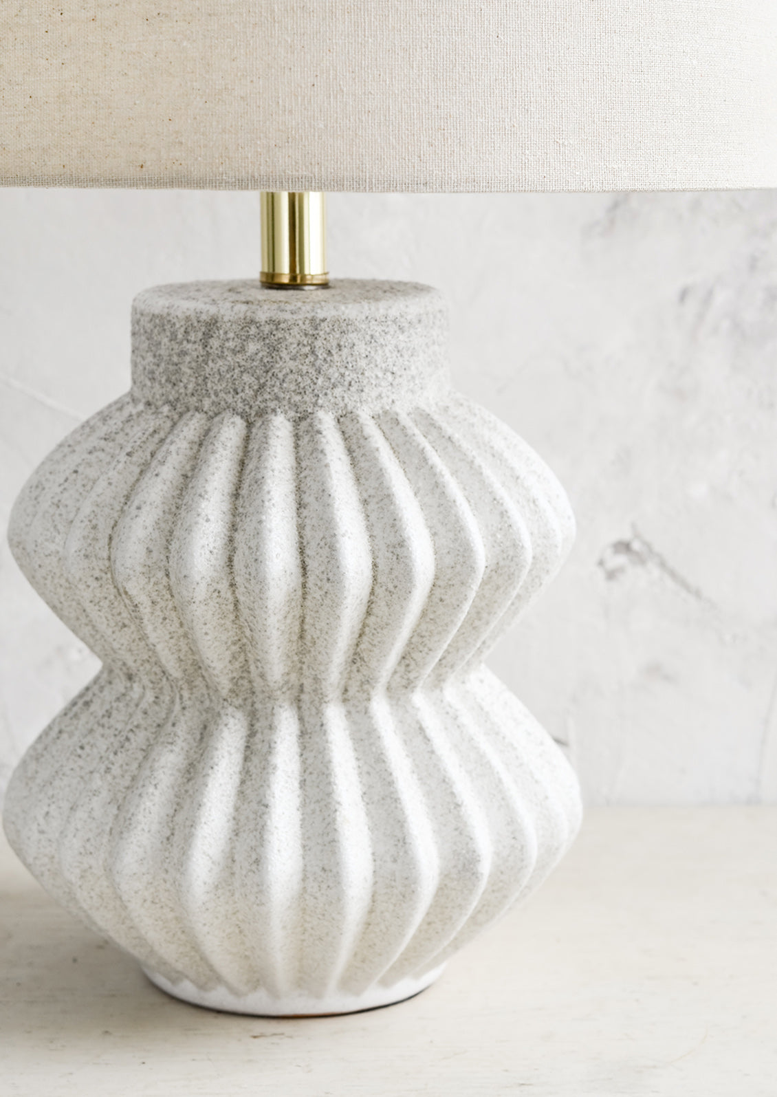 A table lamp with fluted ceramic base in speckled gray.