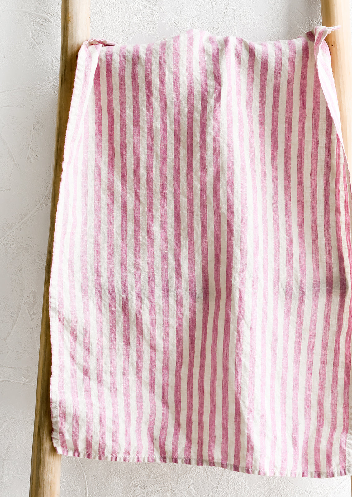 A linen tea towel in pink and white stripe.