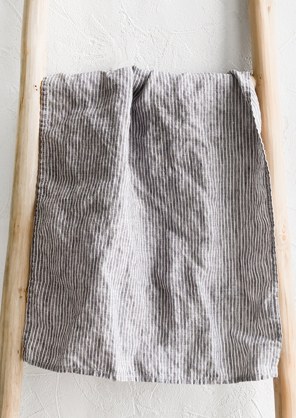 A linen tea towel in grey and white pinstripe.