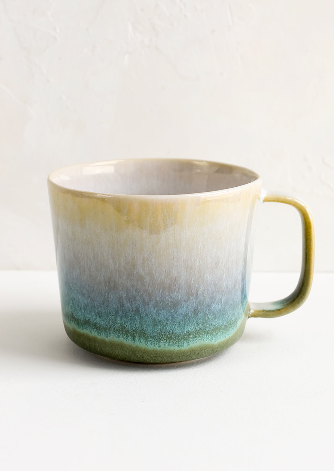 A ceramic mug in green with ombre glaze.