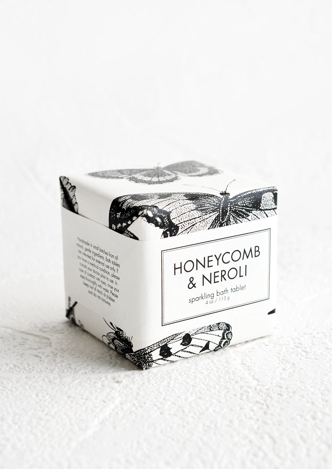 A cube-shaped bath fizzy box with black and white butterfly graphic packaging.