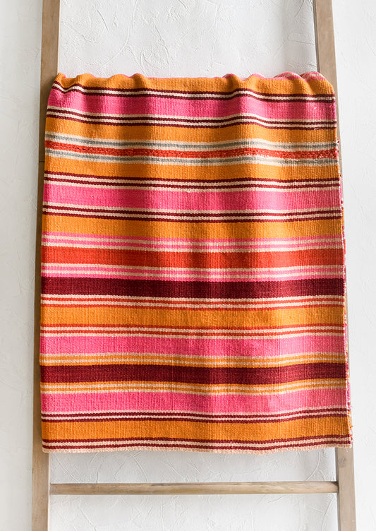 A vintage textile in thin pink, orange and burgundy stripe.