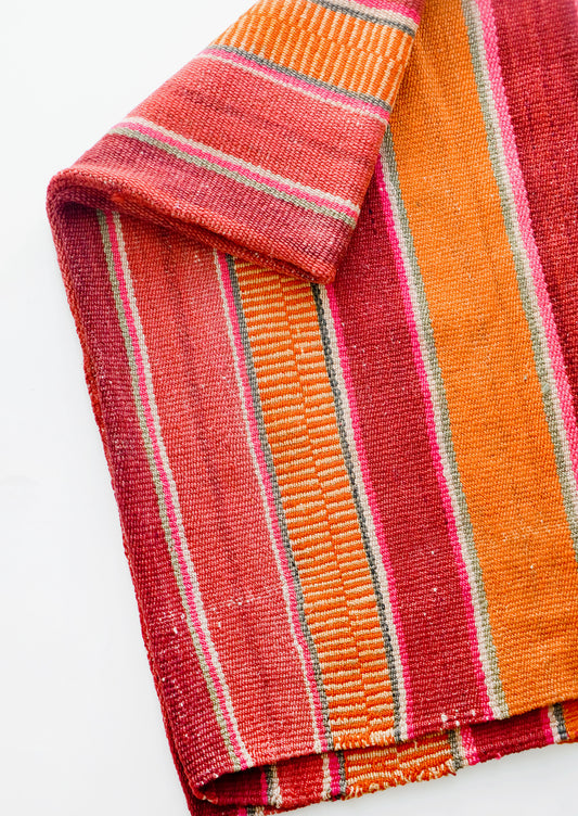 Woven textile intended for use as a rug or blanket, variegated colorful striped pattern.