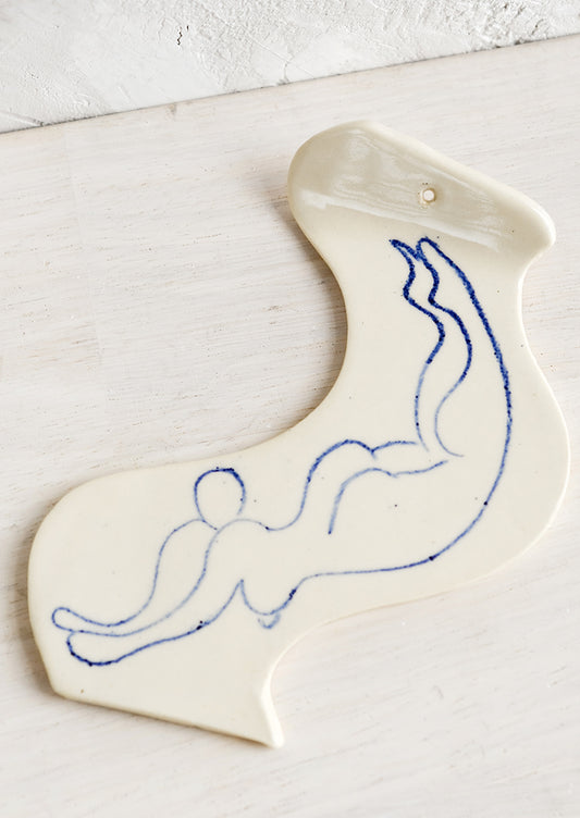 A ceramic incense holder with line drawn naked woman diving.