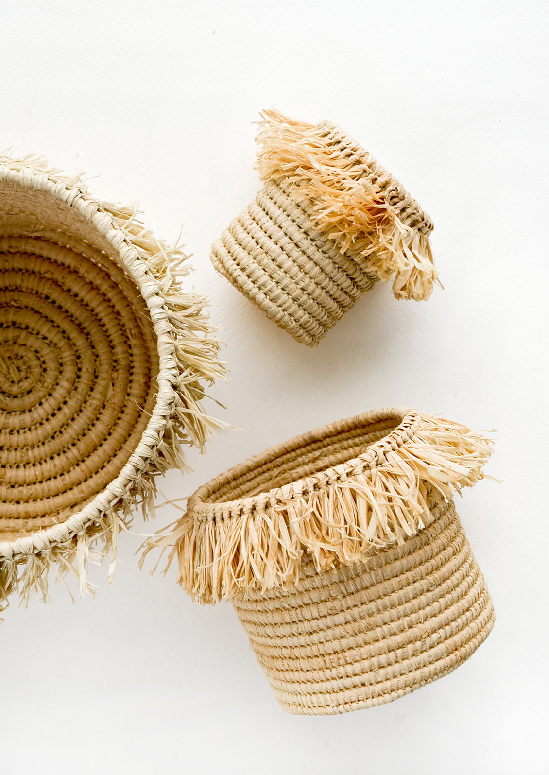 Round, natural raffia baskets with fringed raffia trim around top