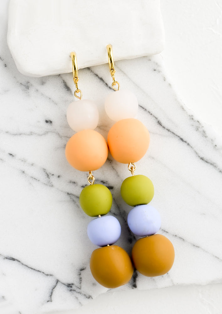 1: A pair of polymer clay drop earrings with colorful balls stacked together.