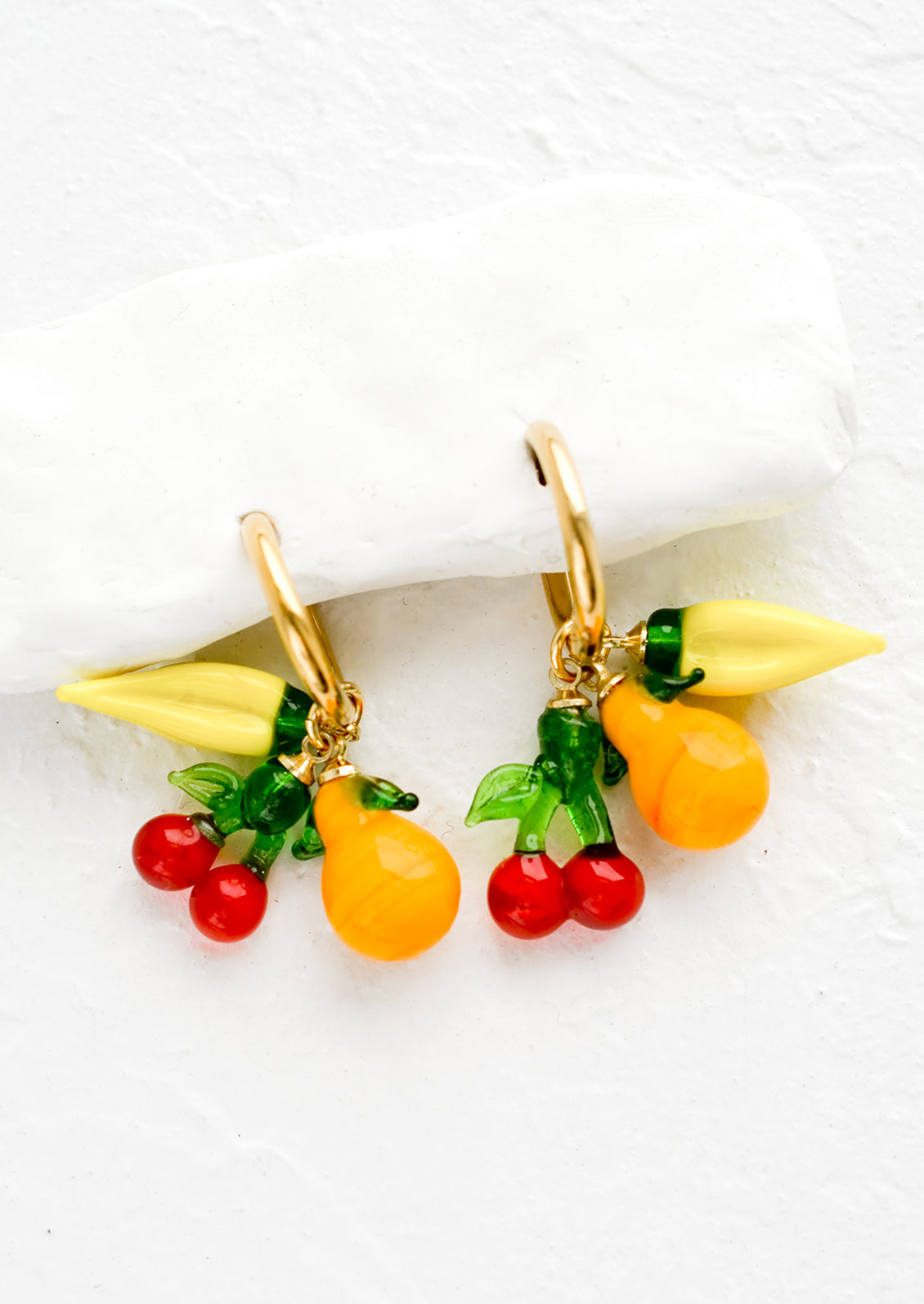 Gold hoop earrings with glass banana, cherry and orange fruit charms.