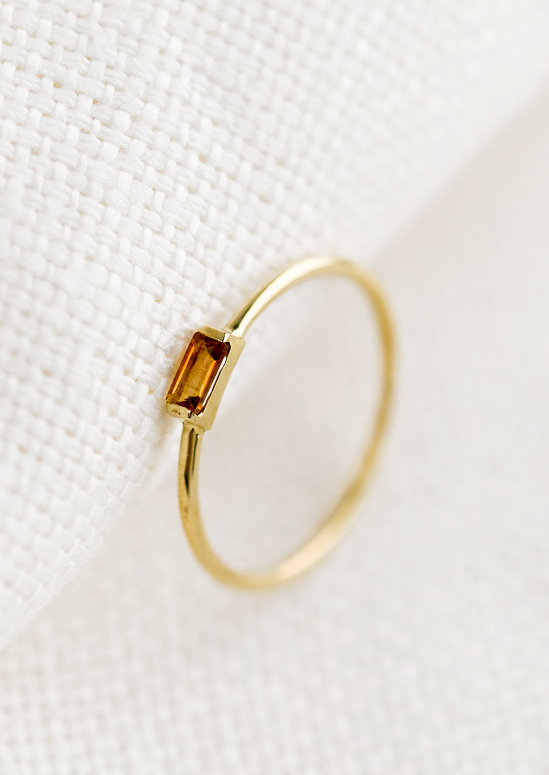 A gold ring with slim baguette stone in citrine.