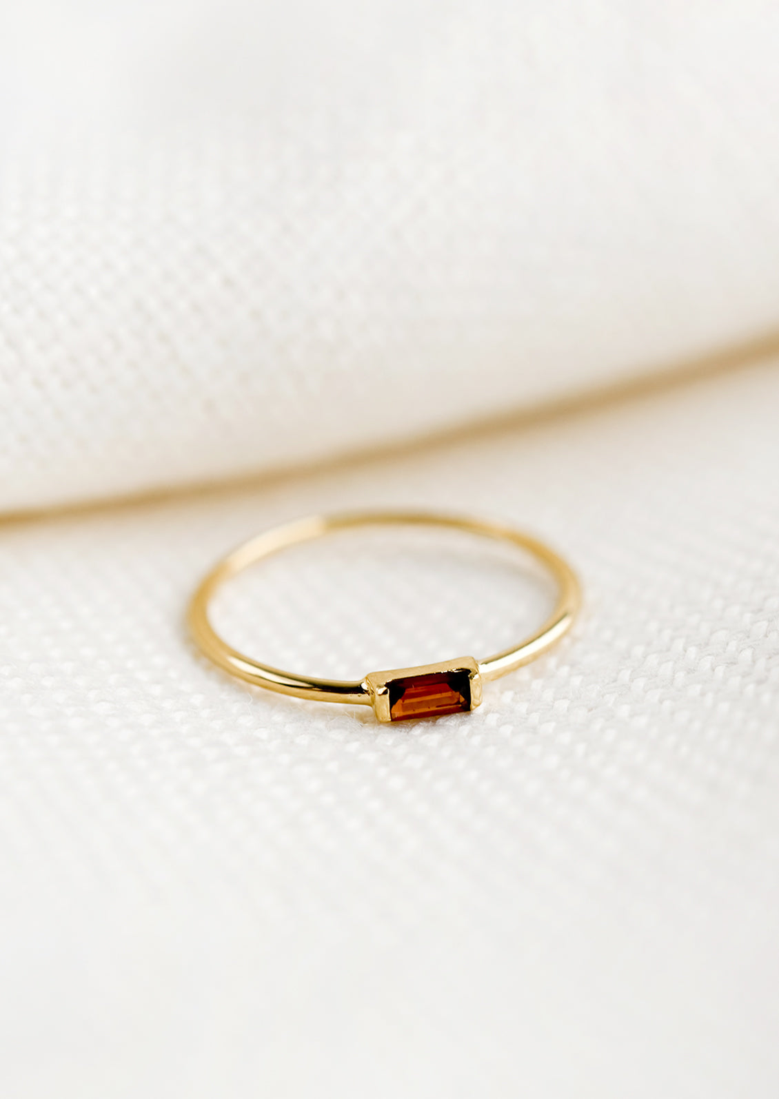 A gold ring with slim baguette stone in garnet.