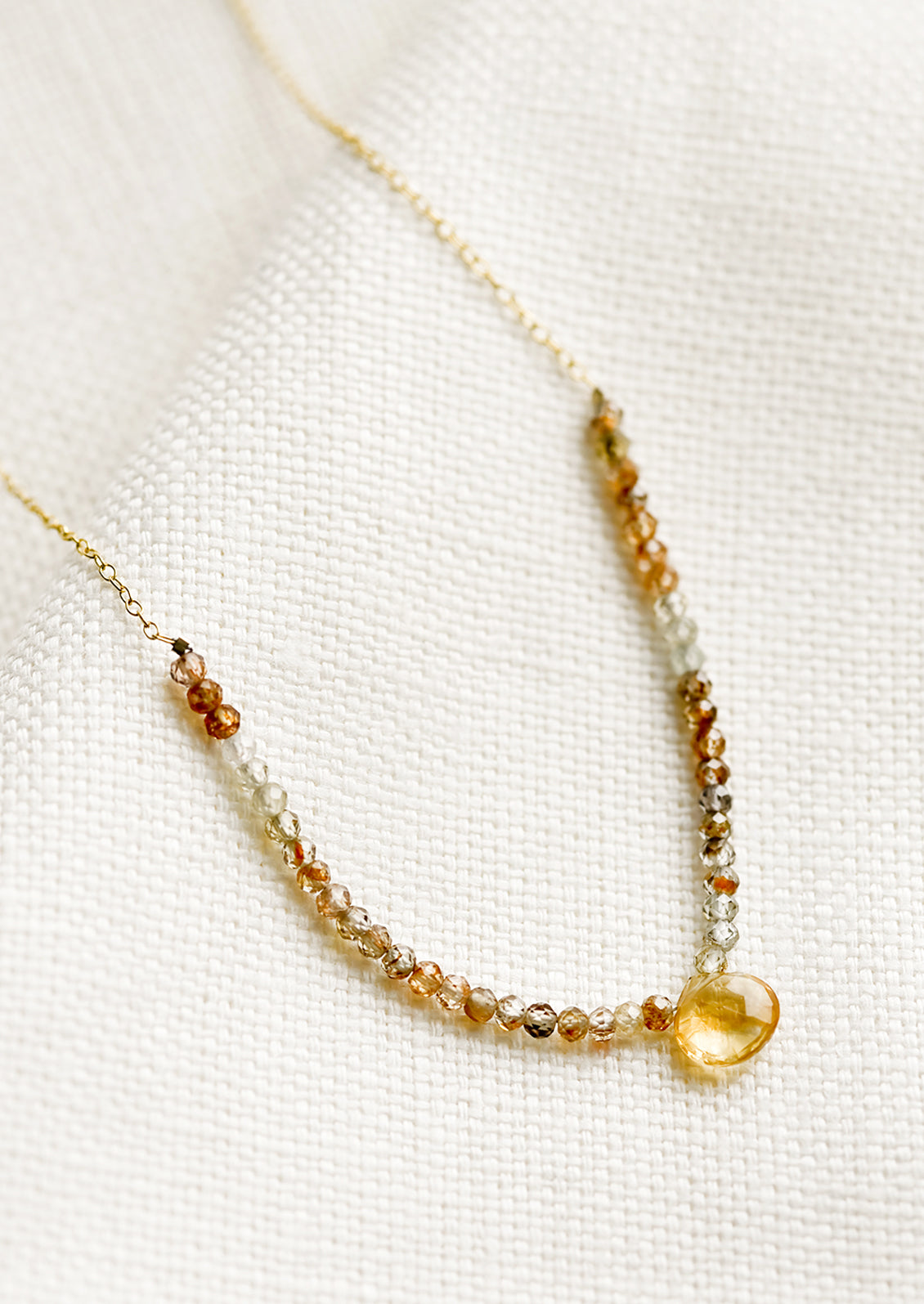 A beaded necklace with small gemstone beads and citrine teardrop.