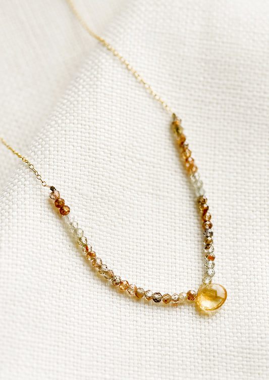 A beaded necklace with small gemstone beads and citrine teardrop.