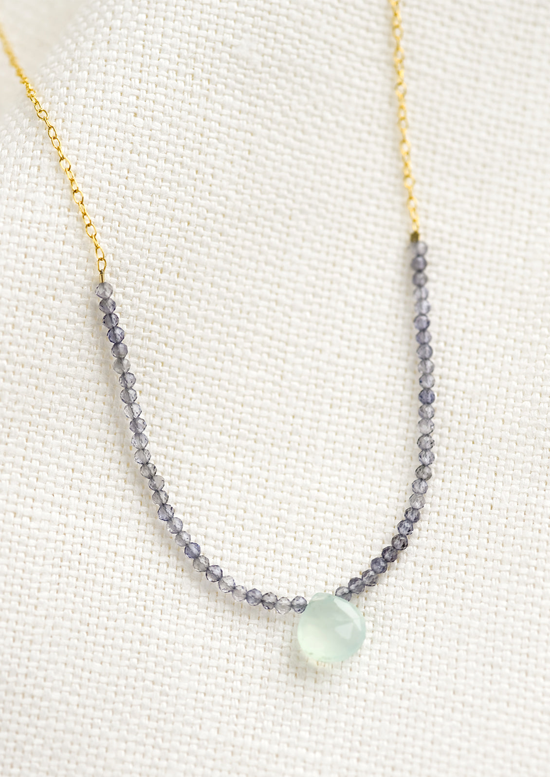 A beaded necklace with small iolite beads and blue chalcedony teardrop.