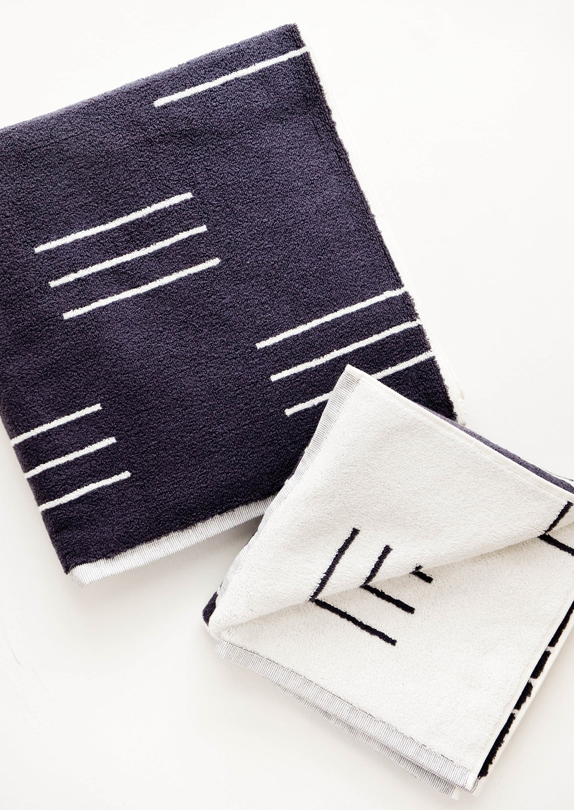 Set of reversible jacquard weave terrycloth towels in dark grey with modern white line print