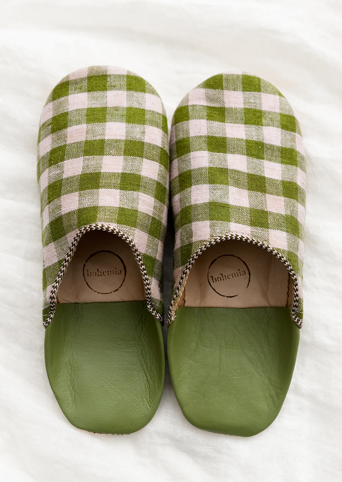 A pair of house slippers in lavender and green gingham fabric.