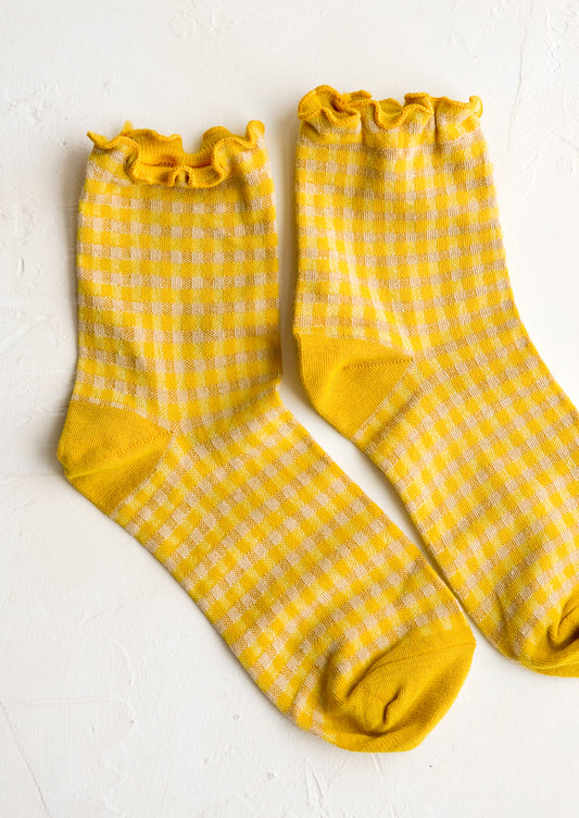 A pair of yellow gingham patterned socks with ankle ruffle.
