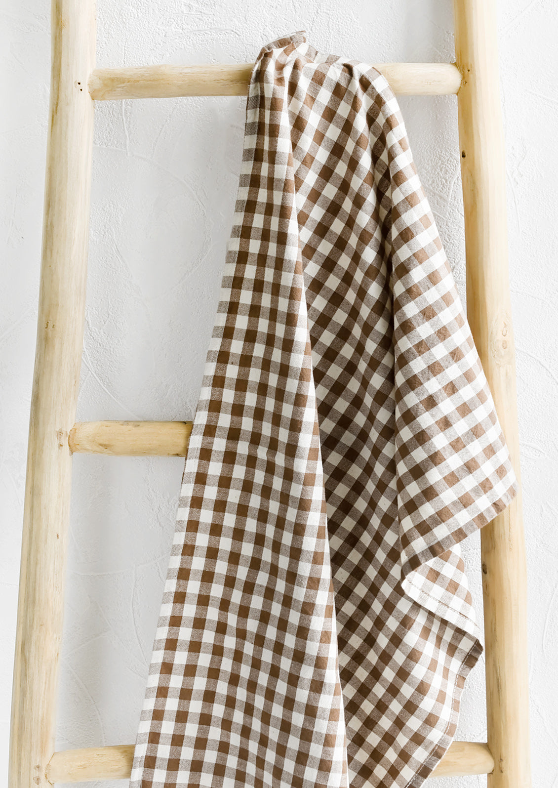 A gingham print tea towel in brown and white.