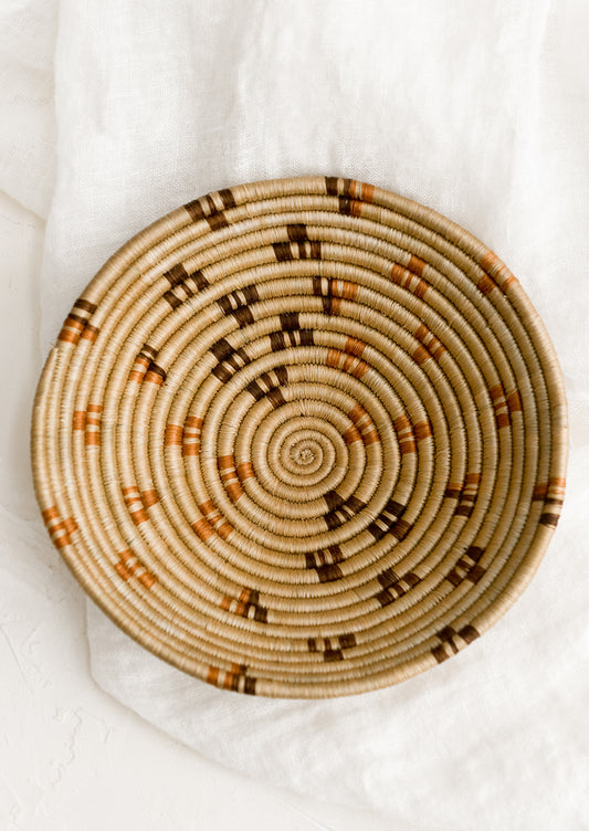 A tan woven bowl with brown and terracotta accents.