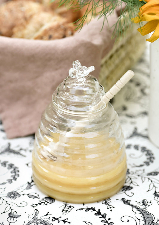 A glass honey jar in the shape of a beehive.