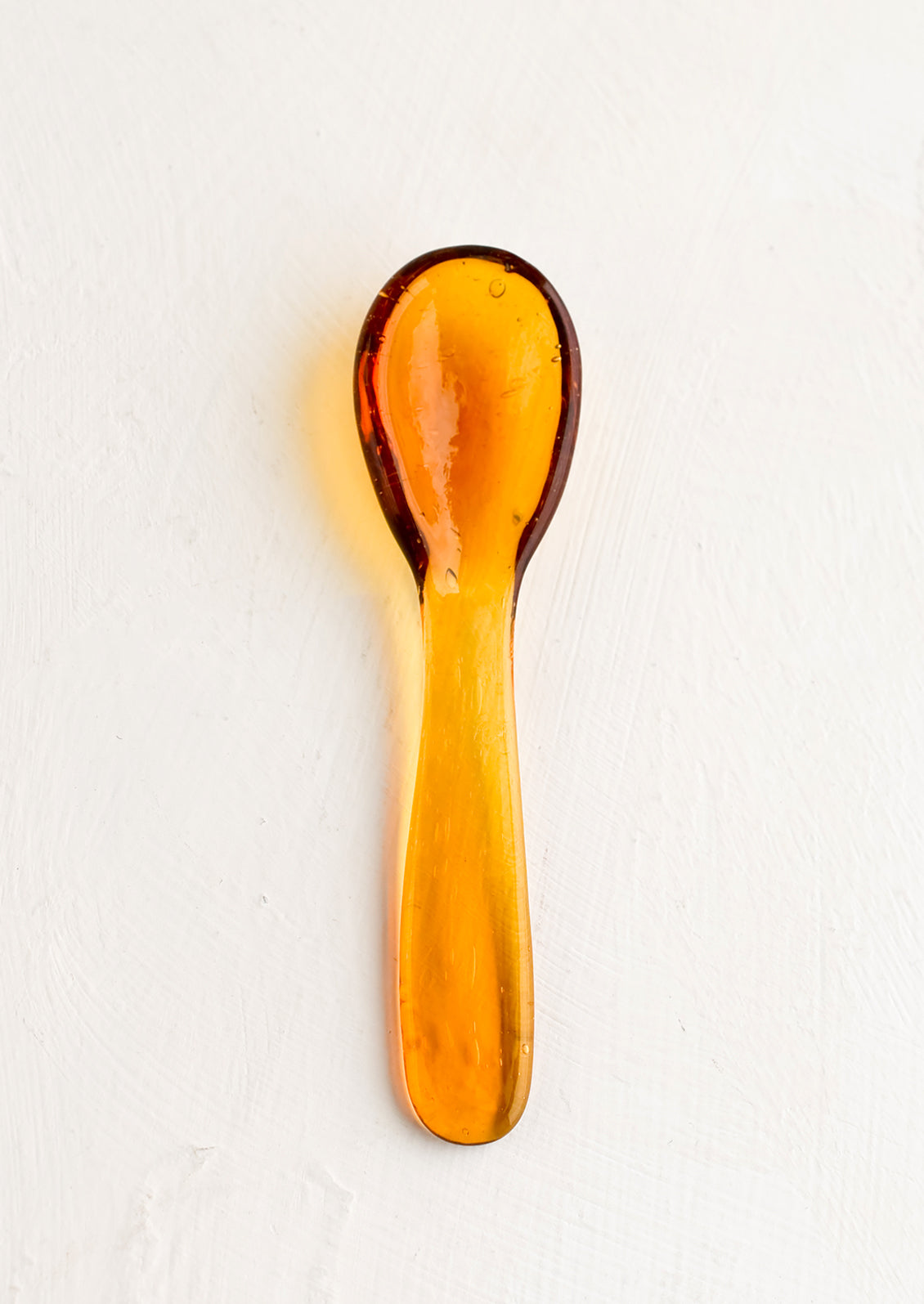 A glass spoon in honey color.