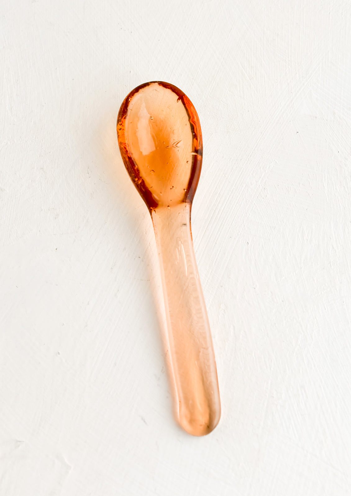 A glass spoon in melon color.