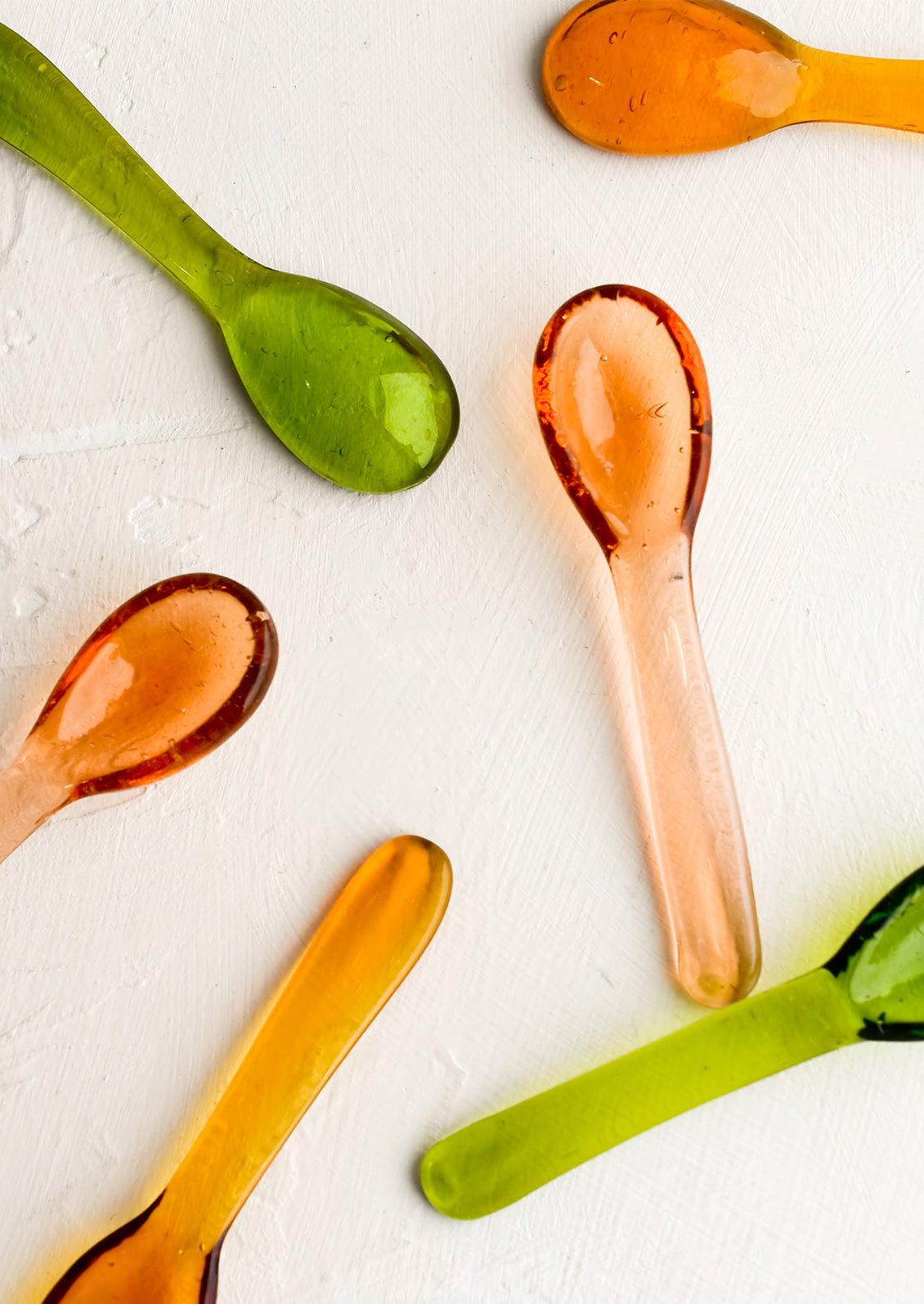 Assorted colors of tiny glass teaspoons.