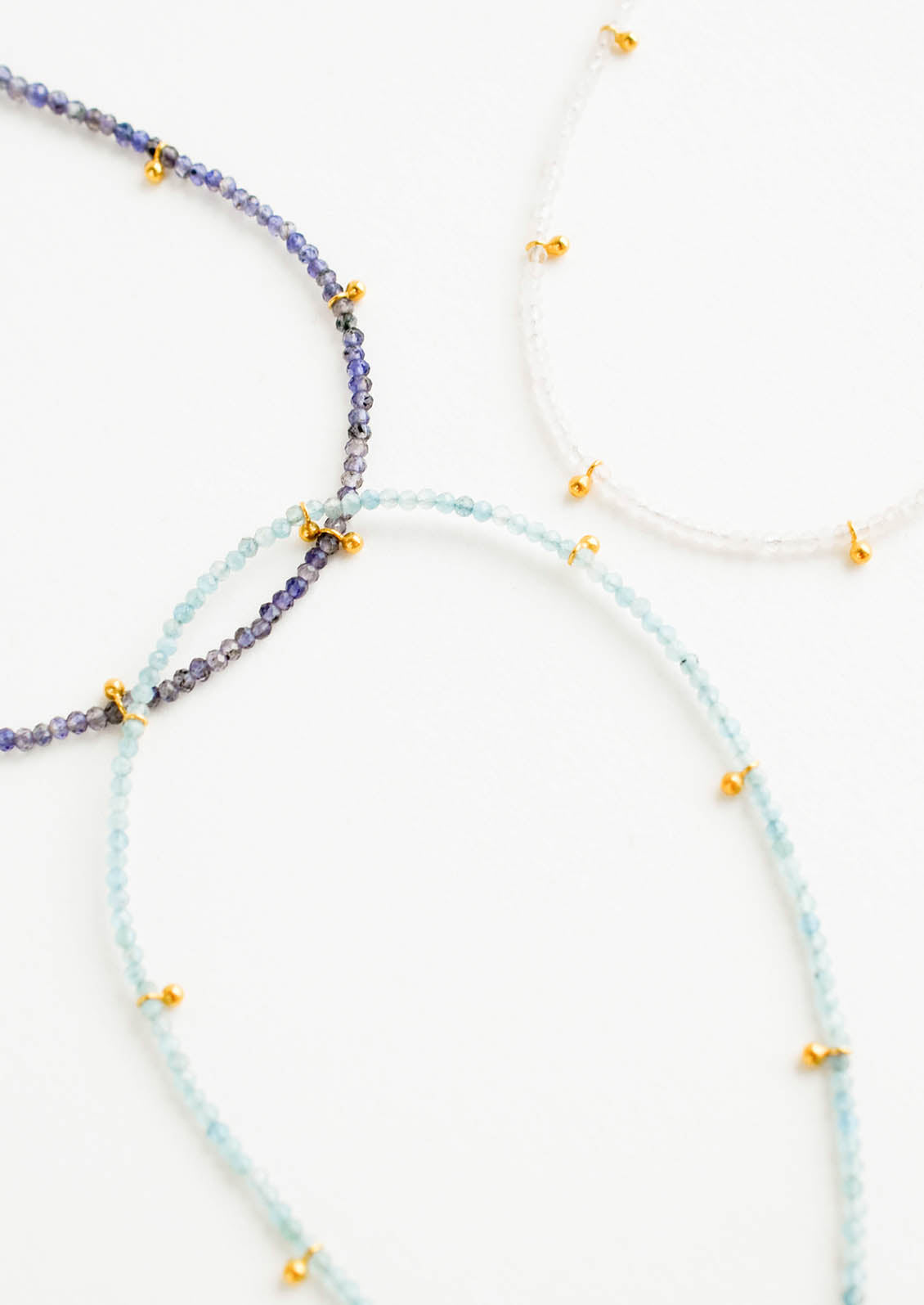 Three necklaces of gemstones and gold beads.