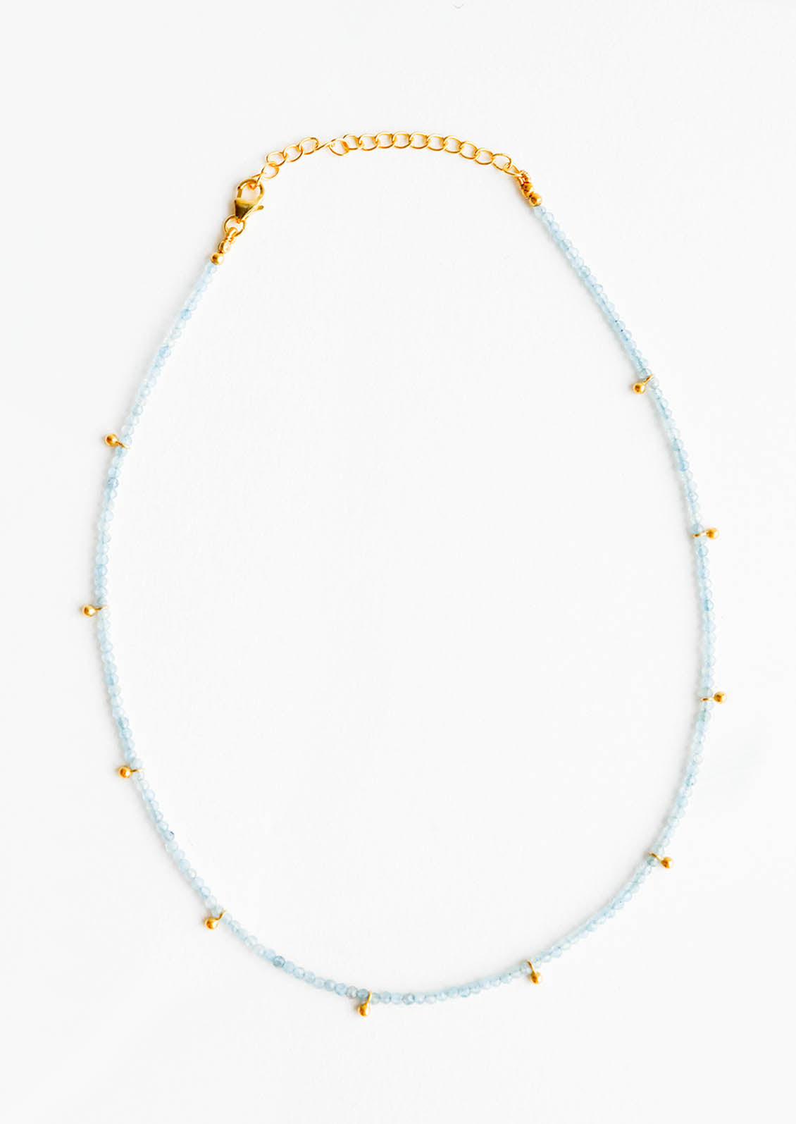 A necklace of clear blue stones with evenly spaced gold beads and a golden chain clasp.