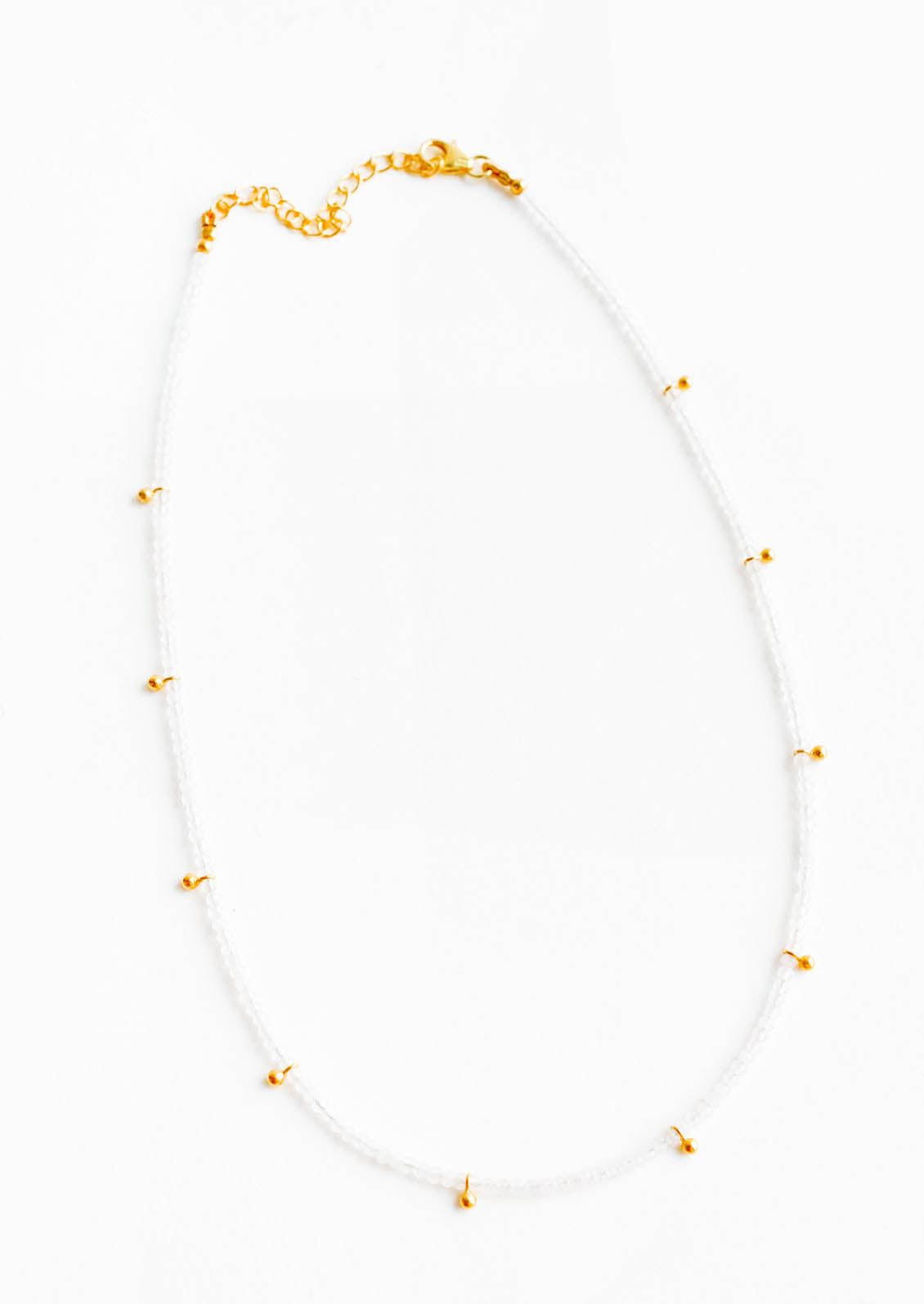 A necklace of clear gray gemstones with evenly spaced gold beads and a golden chain clasp.