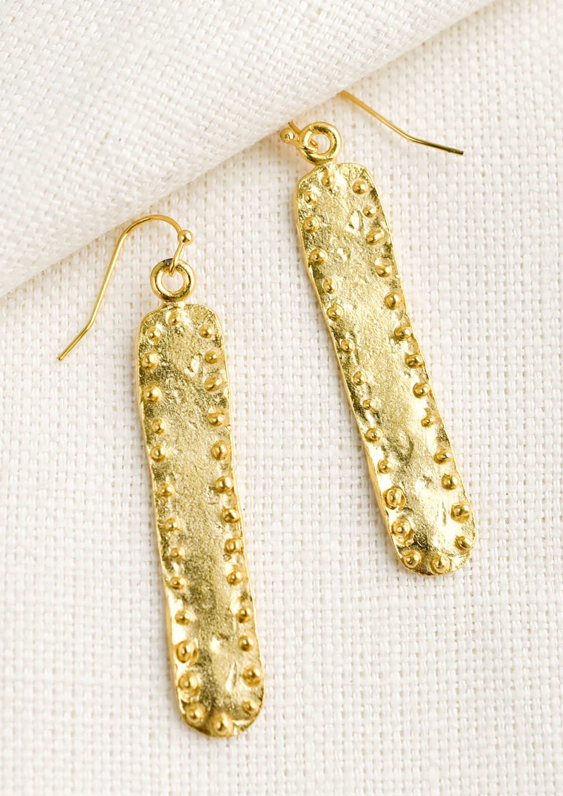 A pair of long bar shaped earrings with raised dot border.