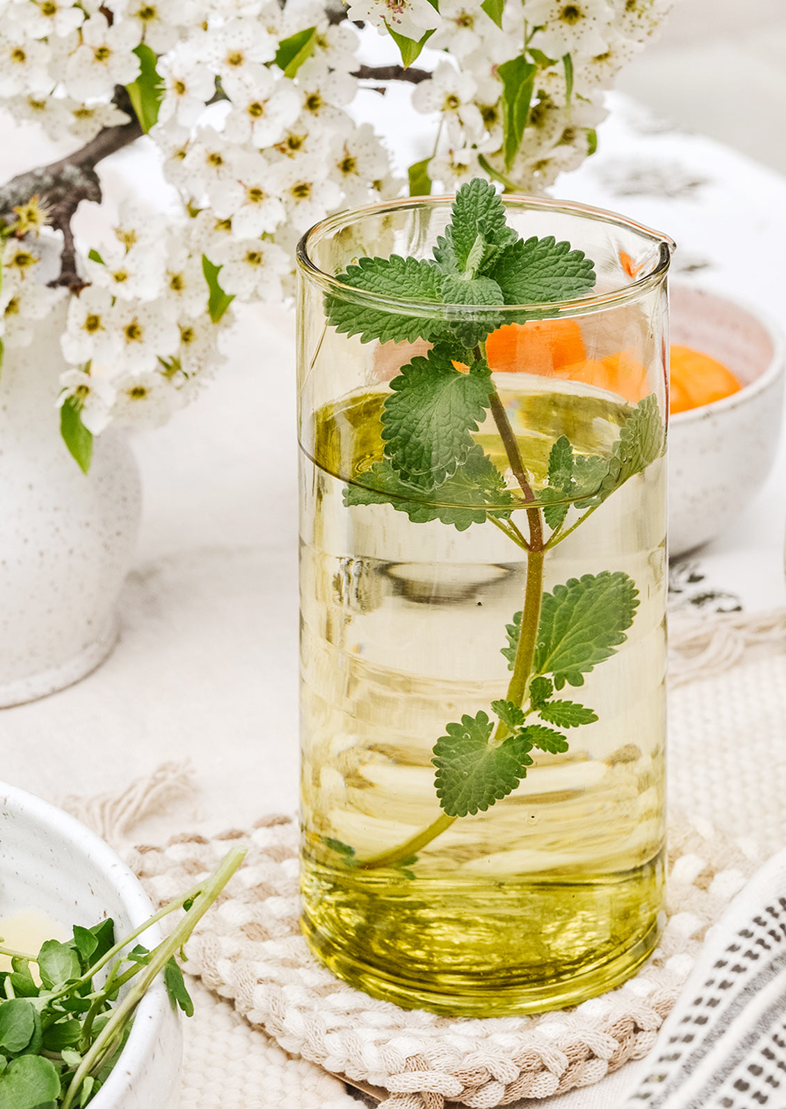 A table setting with water in a pitcher with fresh mint leaves.