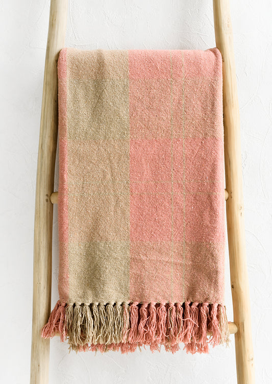 A cotton blank in peach and tan check pattern with fringe trim.