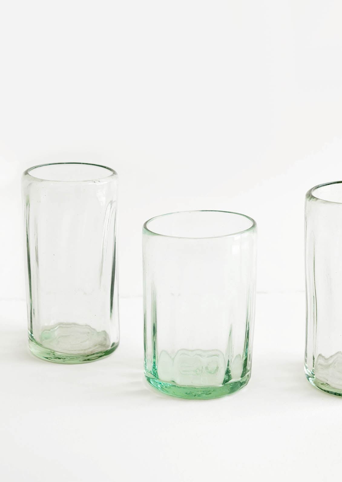 Three horizontally ribbed tumblers in thick green hued glass.