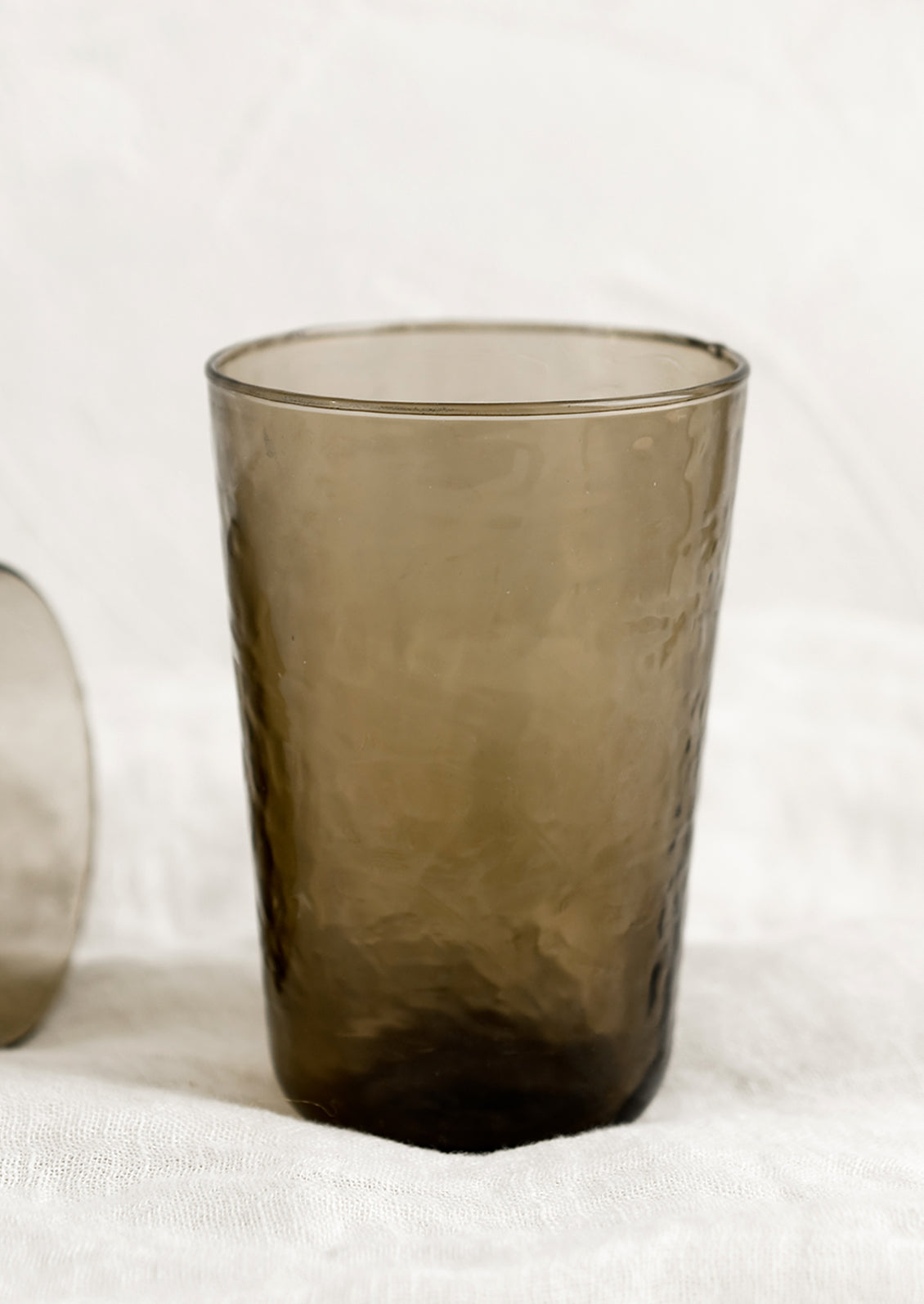 A glass tumbler in hammered texture with brown tint.